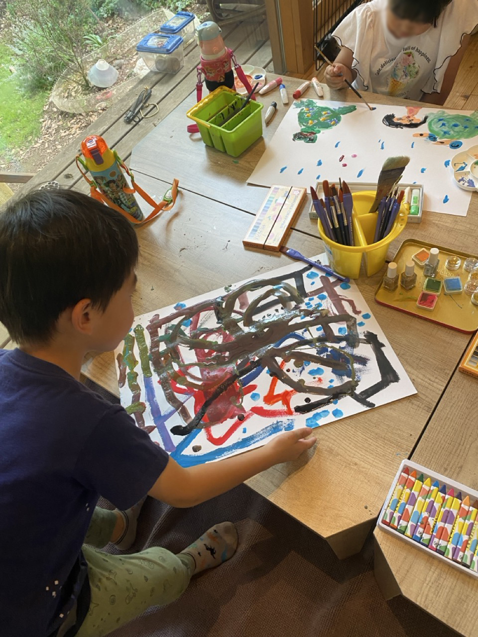 机で制作に取り組む子どもと、色とりどりの画材