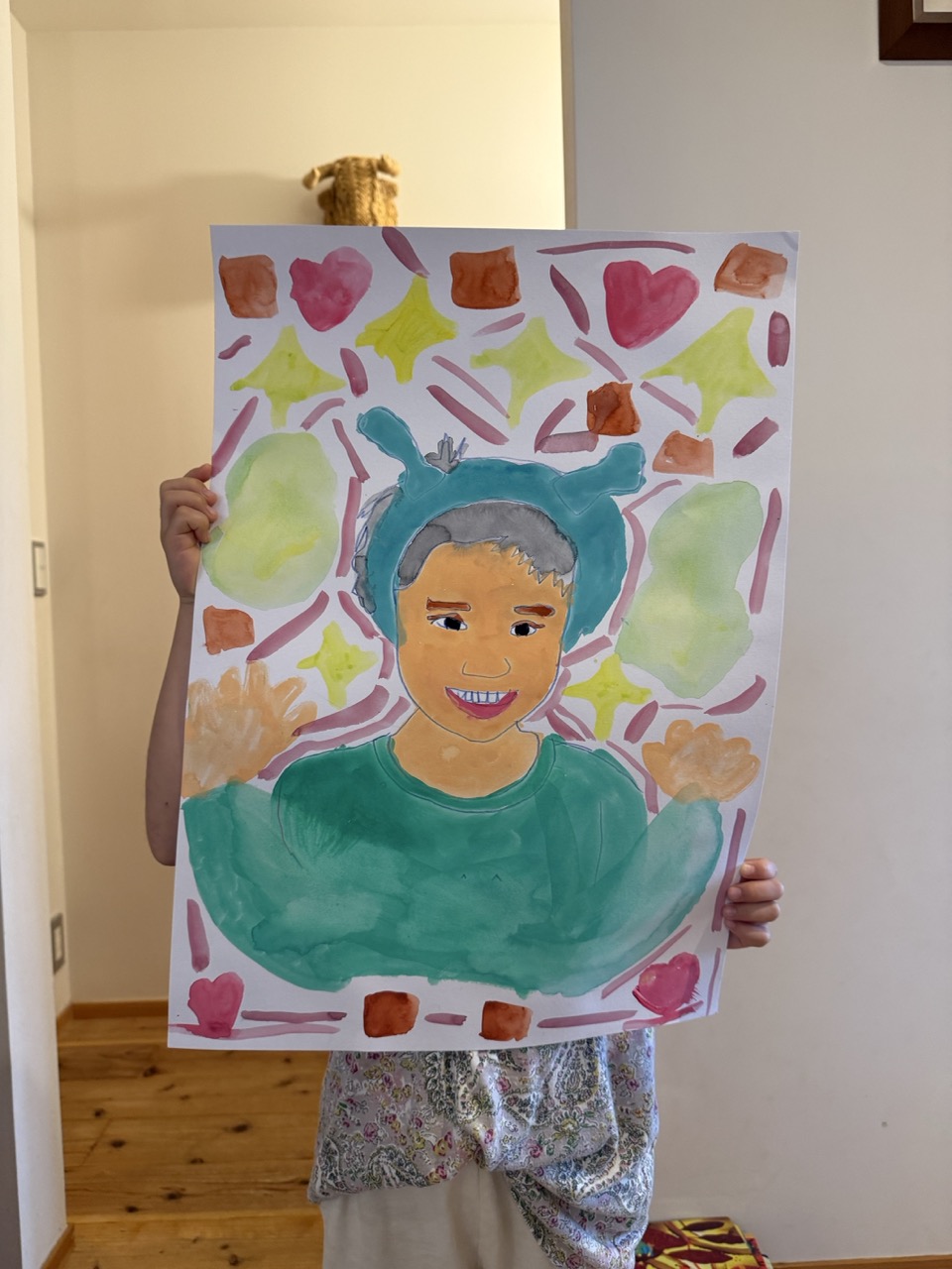 水彩絵の具で描いた自画像を持つ子ども